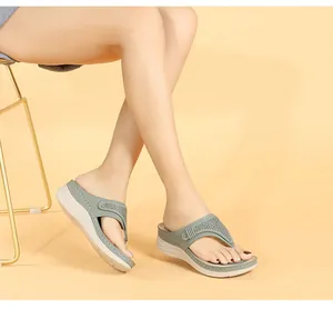 Détail de sandales compensées vert sauge avec motifs floraux découpés au laser et semelle