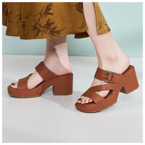 Side view of brown platform sandals with cross straps and metallic buckle detail on feet