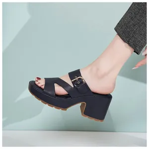 Detail of black platform mule with decorative gold metal buckle and chunky high heel