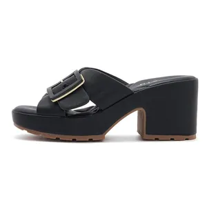 Détail de sandale mule noire à plateforme avec grande boucle dorée et semelle crantée
