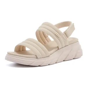 Detail view of cream platform sandals with quilted straps and metallic logo accent