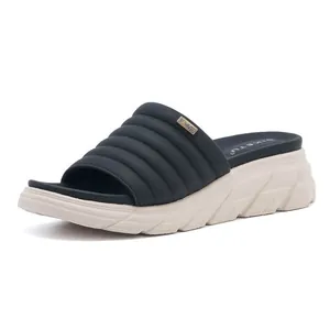 Dettaglio del cinturino trapuntato blu navy con logo dorato sui sandali con zeppa