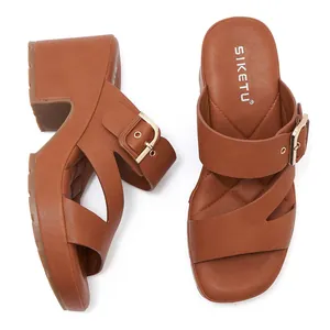 Detail view of brown platform sandals featuring wide cross straps and gold metal buckles