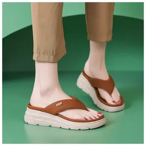 Detail of women's thick platform thong sandals with brown straps and metal logo
