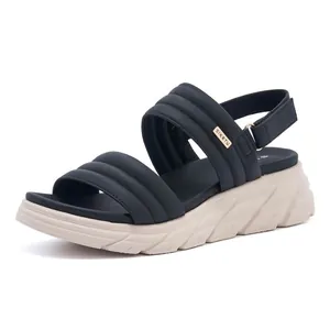 Detail view of double wide straps with quilted texture and golden brand tag on wedge sandals