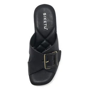 Détail de sandales à brides croisées en cuir noir avec boucle dorée et semelle matelassée