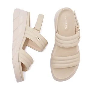 Close-up of beige platform sandals featuring puffy quilted straps and adjustable velcro straps