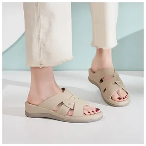 Detailansicht beige Keilsandalen mit gekreuzten Riemen und Metallnieten am Model gezeigt