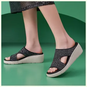 Dettaglio della tomaia in maglia nera glitterata e suola con zeppa dei sandali da donna