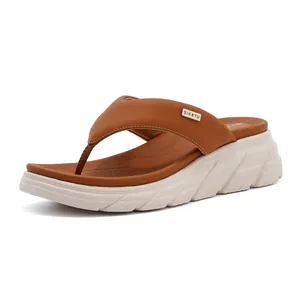 Detail showing the thick foam sole and gold brand logo on brown flip-flop sandals