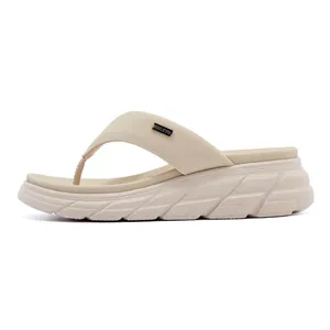 Macro view of beige wedge flip flops showing textured EVA sole and gold logo detail
