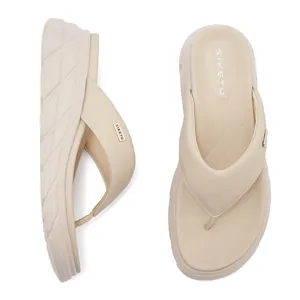 Detailed side view of beige wedge flip flops with gold metal logo and anti-slip texture