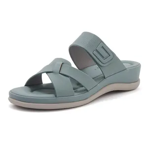 Dettaglio di sandali con zeppa grigio-blu con cinturini incrociati e logo geometrico a rilievo