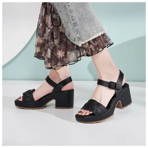 Détail de sandales noires à semelles compensées avec brides en cuir tressé et boucle