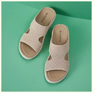Dettaglio del cinturino in maglia beige e suola a zeppa di sandali leggeri da donna