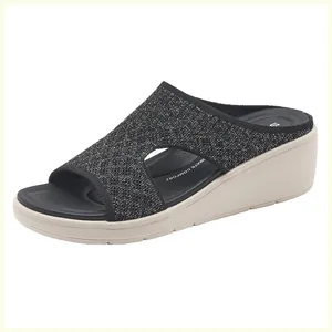 Dettaglio di sandalo con zeppa in mesh glitterato nero e soletta ultra confortevole
