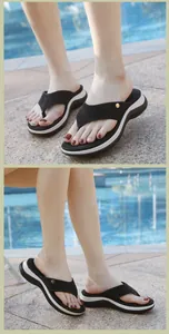 Détails des brides en strass et semelle compensée de tongs noires portées au bord de l'eau