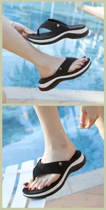 Gros plan de tongs compensées noires avec brides en strass et boucle dorée au bord de l'eau