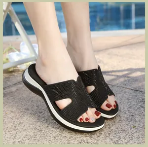 Detailed close-up of rhinestone embellished wide strap on black platform wedge sandals