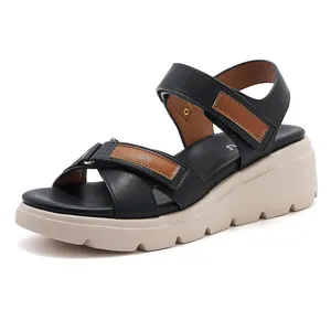 Dettaglio di sandali con zeppa in pelle nera con cinturini a strappo e suola antiscivolo