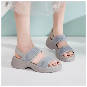 Nahaufnahme grauer Plateau-Sandalen mit gestrickten elastischen Riemen am Fuß