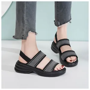 Nahaufnahme schwarzer Plateausandalen mit gestreiften Riemen und elastischem Fersenband