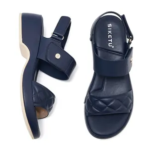 Deep blue wedge sandals featuring quilted details and metallic logo buckle on white backdrop