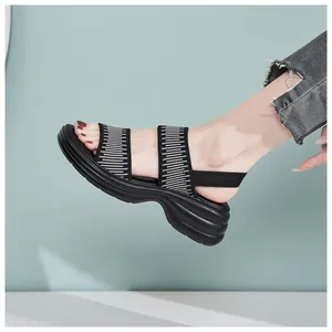 Detailansicht der Plateau-Sandalen mit schwarz gestreiften Gummizügen und Wellensohle