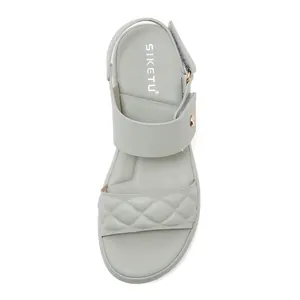 Close-up of sage green wedge sandals with quilted straps and adjustable velcro strap