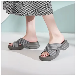 Side view of women's thick-sole wedge slide sandals with grey crisscross woven straps