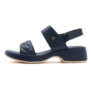 Close-up of navy blue quilted wedge sandals with velcro strap and metal logo detail
