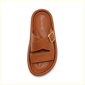 Détail de sandales en cuir marron avec boucle carrée dorée et semelle épaisse confortable