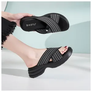 Detail view of women's black wedge slippers with criss-cross woven straps and platform sole