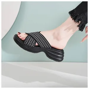 Close-up of black platform slide sandals with textured cross straps and thick wedge sole