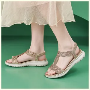 Nahaufnahme goldener Sandalen mit Strasssteinen, elastischem Fersenriemen und weißer Sohle