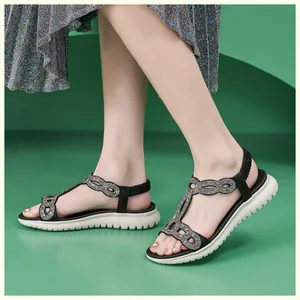 Detail der glitzernden Strasssteine an T-Riemchen-Sandalen mit dicken weißen Sohlen