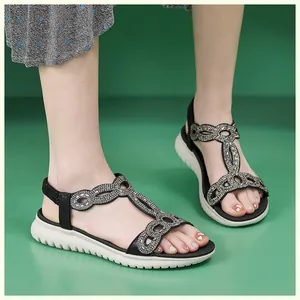Detailaufnahme schwarzer Sandalen mit Strassverzierung und klobiger weißer Sohle