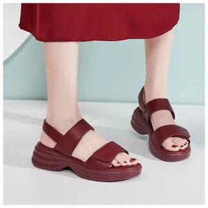 Detail view of burgundy platform wedge sandals with adjustable velcro straps on feet