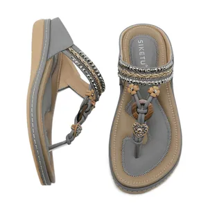 Grey bohemian wedge sandals with rhinestones and floral details on a white background