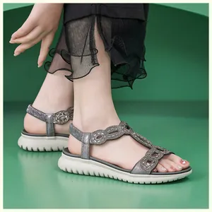 Detailansicht der Keilsandalen mit Strassriemen und weißer, gezackter Gummisohle im Profil