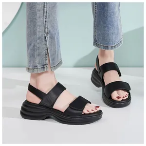 Close-up of black platform sandals with dual straps and wave-textured wedge soles