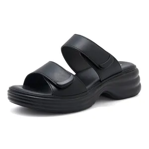 Dettaglio di sandali neri con zeppa, cinturini in velcro regolabili e suola a onde spesse