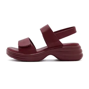 Detail view of burgundy wedge sandals featuring dual hook-and-loop straps and wavy sole
