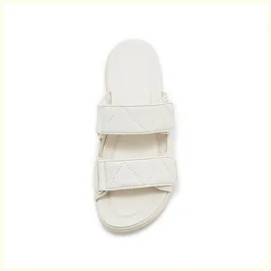 Detalle de sandalias de mujer blanco crema con patrones de triángulos acolchados y dos tiras