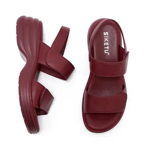 Detail of burgundy platform sandals with velcro straps and wave-shaped thick sole