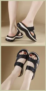Détail de sandales compensées pour femmes avec lanières en cuir noir et boucles cloutées