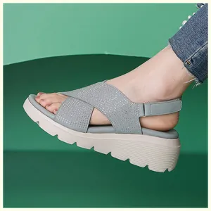 Dettaglio di sandali grigi con zeppa, cinturini in strass e velcro regolabile sul tallone