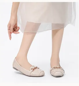 Detail van beige loafers met vierkante neus, ruitpatroon en goudkleurige metalen ketting