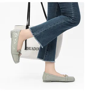 Detail van saliegroene lakschoenen met ruitpatroon en goudkleurige metalen kettingsluiting