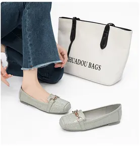 Detailopname van glanzende lichtgroene loafers met reliƫf en een gouden kettinggesp